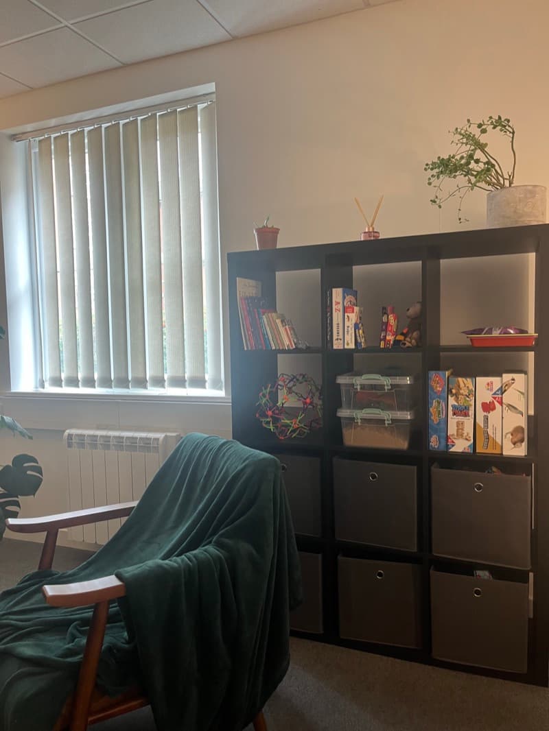 Therapy room shelving with games, toys, books, and fidgets for children